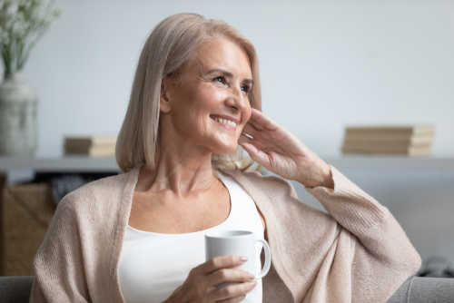 happy woman sitting on couch drinking coffee